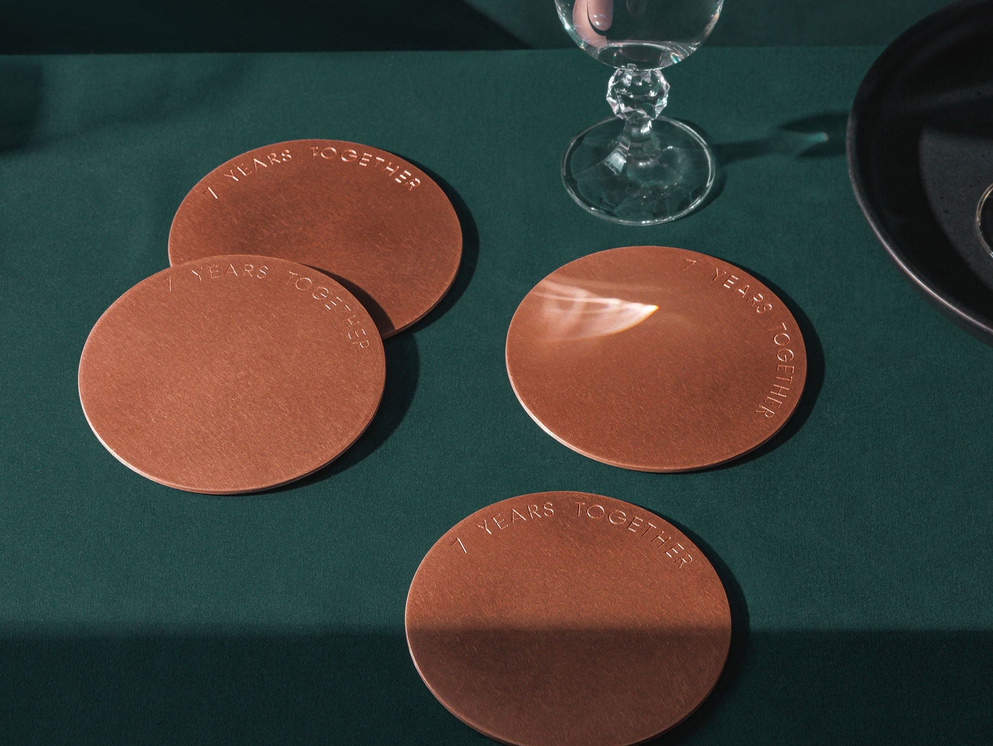 A set of 4 copper coasters engraved with the message "7 Years Together". The coasters are made by Empire Copper by Hayes Home.